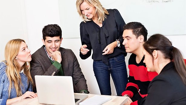 Bilden föreställer en grupp människor som för dialog framför en dator.